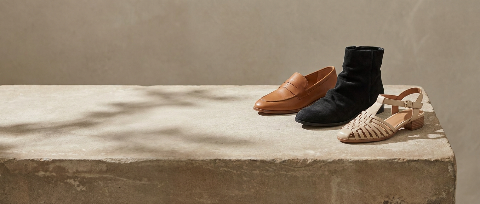 Three pairs of comfort shoes on a warm stone plinth